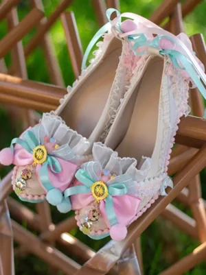 Pair of matching sky blue rococo lolita pumps displayed from oblique top view, featuring dual-tone bows, intricate lace trim, pink-blue hanging ribbons, outdoor garden setting