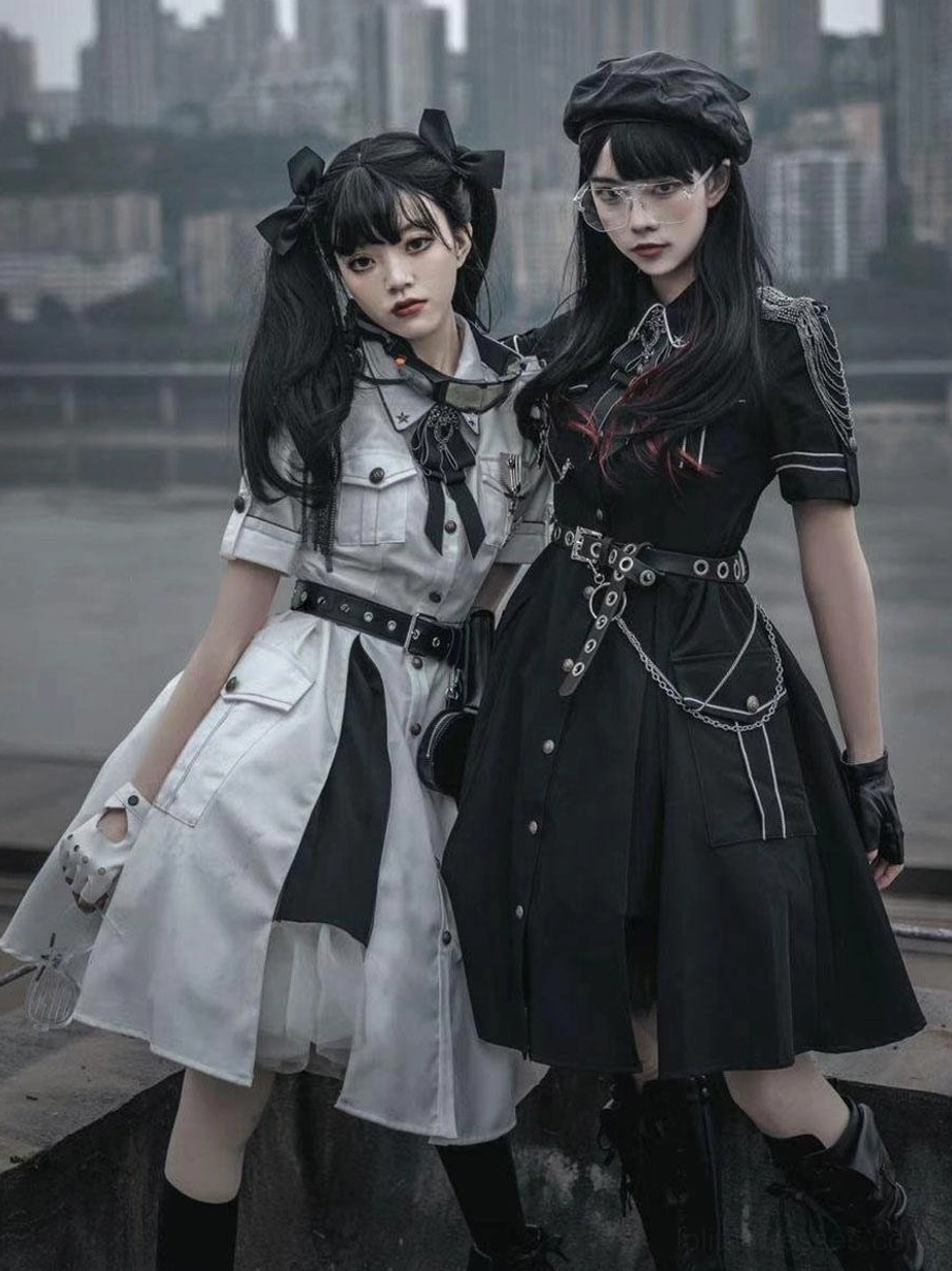 Two female models outdoor riverside wearing military Lolita dresses one white one black with beret hats waist chains and goth matching accessories