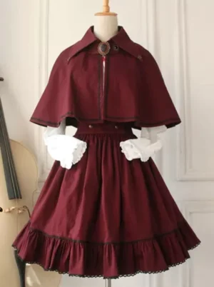 Military lolita outfit wine red tone with lace-trimmed hem and vintage brooch detail, three-quarter front angle with cello prop