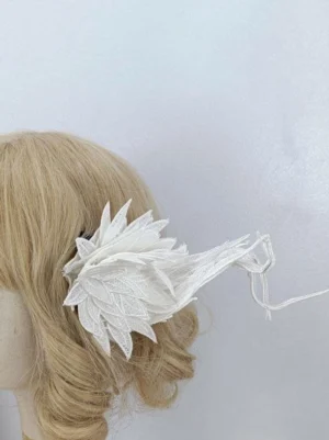 Mini white wing hair clip lolita accessory close-up side view on blonde wig mannequin showcasing delicate leaf embroidery and thin long tail appendage design