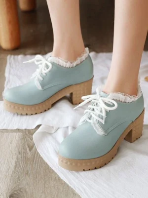 Mint blue Lolita chunky heel platform shoes with ruffled lace trim and textured wooden-style thick sole, round toe design close-up side view of feet on wooden floor
