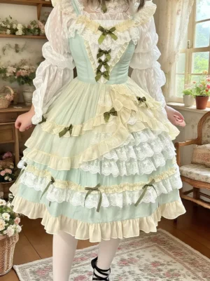 Mint green and cream hime lolita dress sleeveless with layered lace tiered skirt and dark green ribbon bows front partial view vintage cottage setting