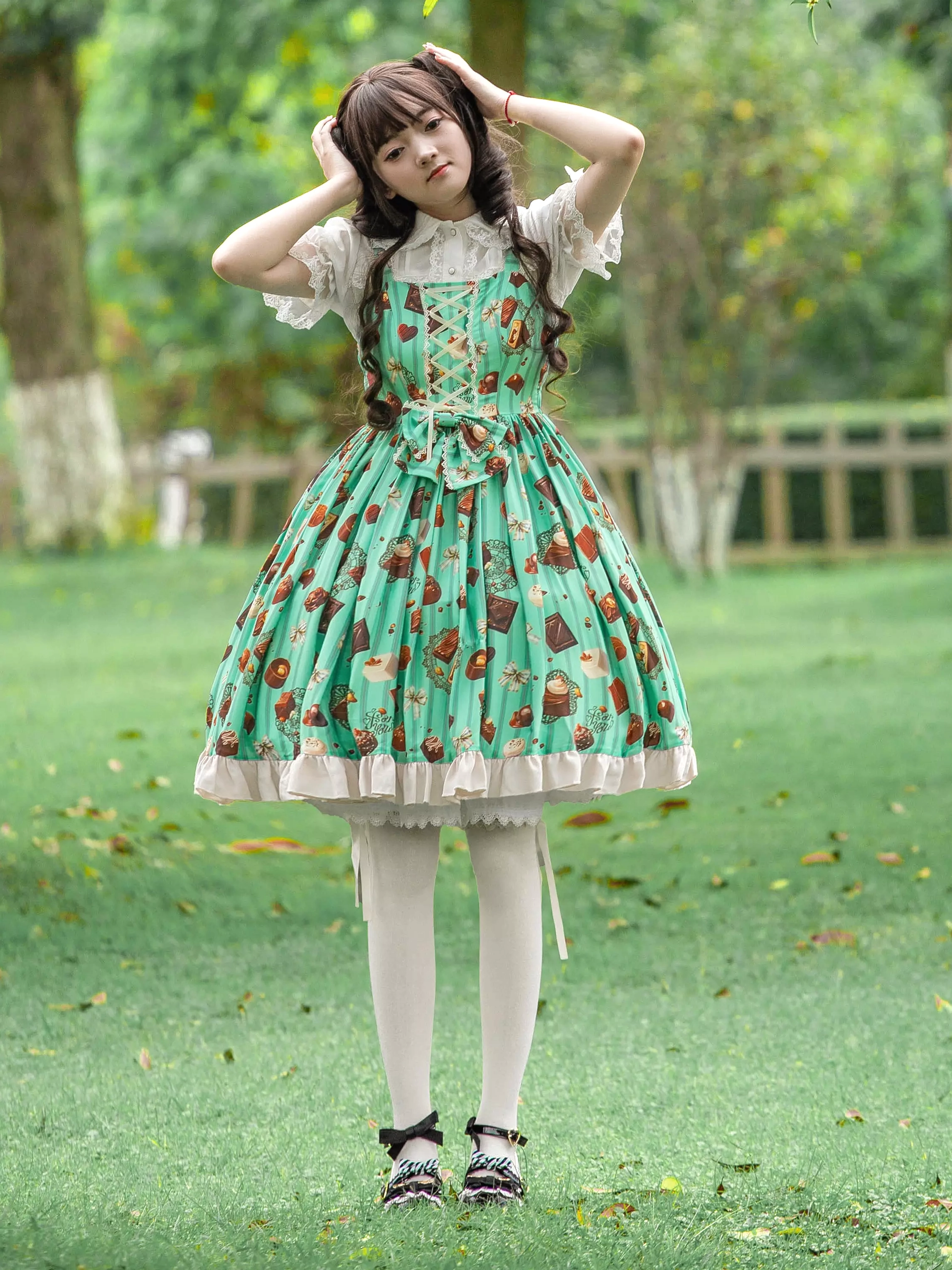 Mint green chocolate cake print sweet Lolita JSK dress full body front view with ruffled hem worn by female model in outdoor park setting