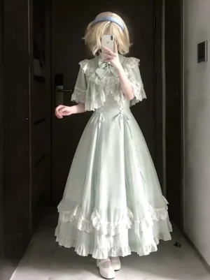 Mint green sweet lolita dress with dramatic cape collar and lace trim worn by model with blue headband, front-facing mirror selfie showing full dress silhouette and decorative bows