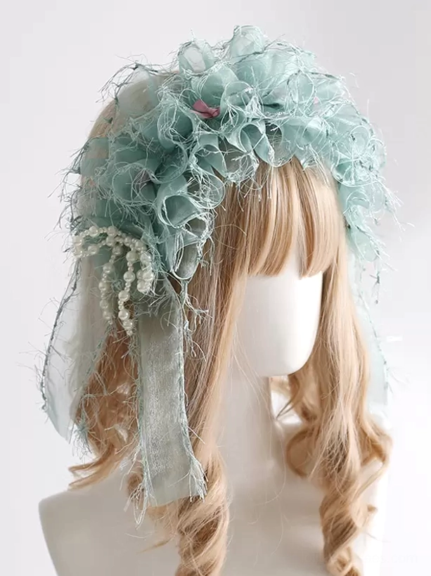 Mint green sweet lolita headdress with frayed organza ruffles and pearl tassel decor featuring tiny pink accents, displayed on blonde wig from three-quarter angle