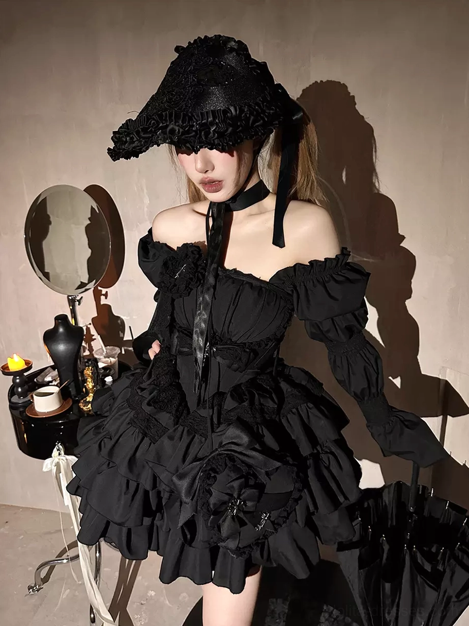 Model wearing off-shoulder black Gothic Lolita dress with ruffle wide-brim hat, detachable puff sleeves, layered ruffle skirt, cross details, and vintage indoor studio setting