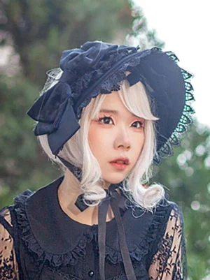 Navy blue Lolita bonnet headdress with lace trimmed edges and satin bow, modeled outdoors with white wig