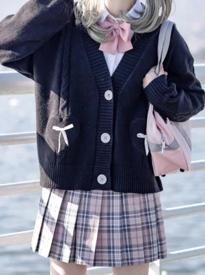 Navy blue lolita cardigan sweater with bow pockets and pink bow tie accent displayed on model with pink backpack
