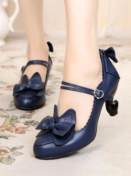 Navy blue sweet lolita heels with heart-shaped ankle strap and round toe design on floral carpet background, side close-up worn