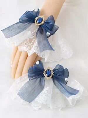 Navy blue organza wrist bow lolita accessory with jeweled gemstone ornament and ruffled pearl-accented lace base on mannequin hand display
