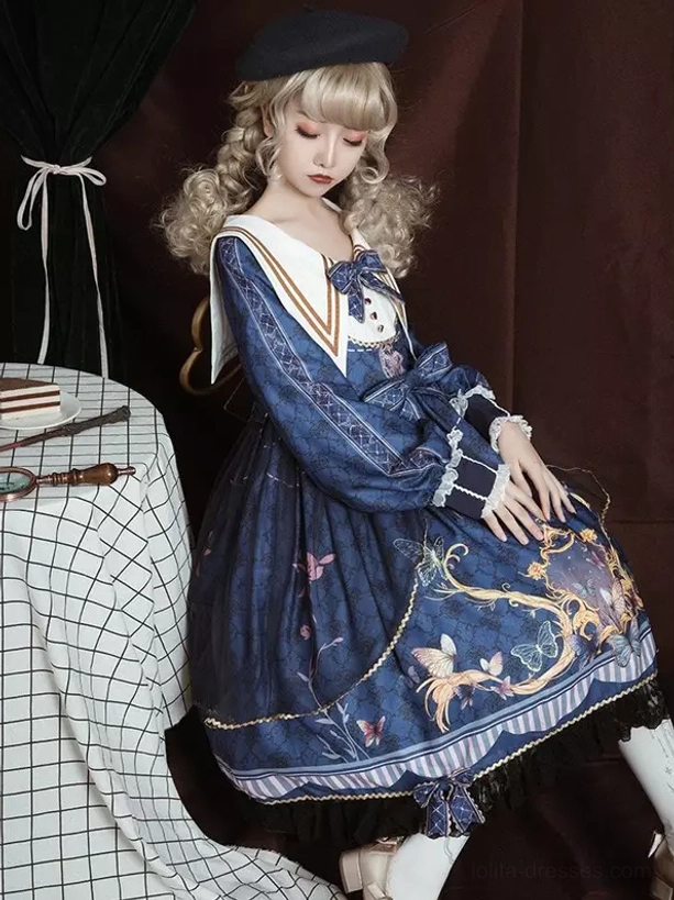 Navy sailor lolita OP dress sitting pose showing floral vintage print, ruffled long sleeves, sailor collar, and full skirt drape with lace hem