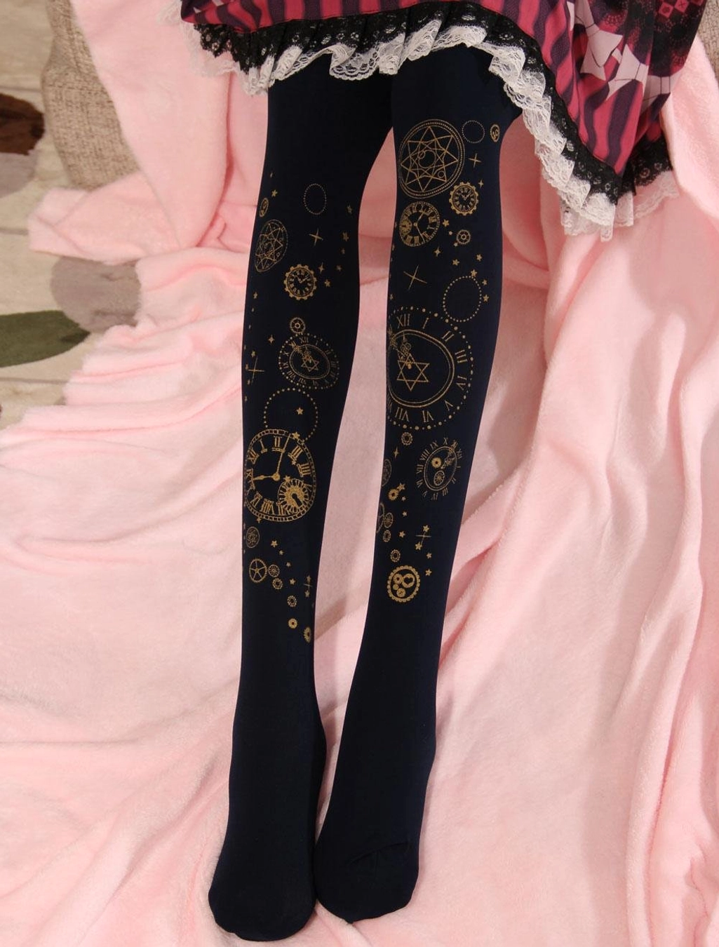 Navy dark blue velvet lolita pantyhose featuring gold foil clock face and hexagram hot stamping, paired with frilled lolita skirt on pink plush fabric background - leg showcase