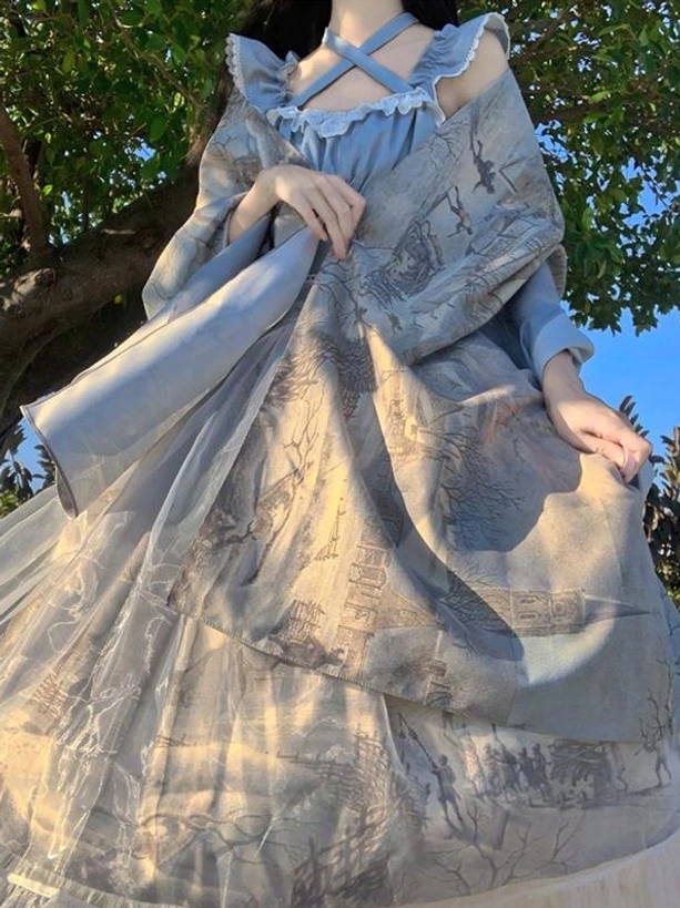 Off-shoulder blue landscape print classic lolita dress with cross strap detail and lace trim on bodice, side front view outdoor posing under tree