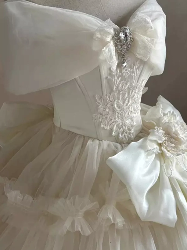 Side front view of off-shoulder Lolita wedding dress with rhinestone bow embroidered bodice and waist 3D floral bow decoration
