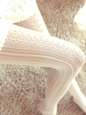Off-white delicate lace cut-out lolita tights with vertical floral hollow pattern close-up detail on leg showing sheer embroidered fabric texture and romantic aesthetic