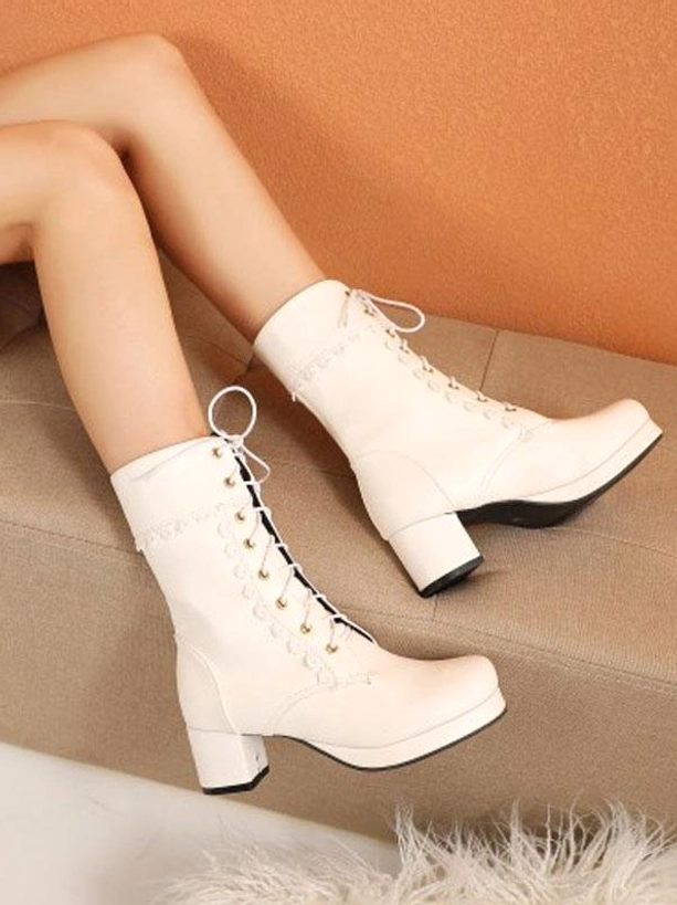 Off-white cream lace-up Lolita ankle boots with round toe and block heel featuring white floral lace trim, worn on model's feet on beige sofa