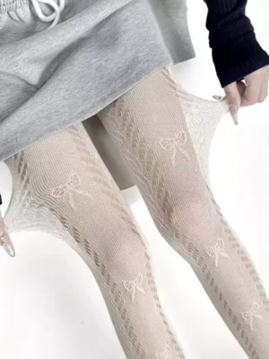 Off-white lolita bow lace pantyhose close-up with twisted hollow mesh pattern and delicate bow details worn with gray top for sweet lolita coordinate