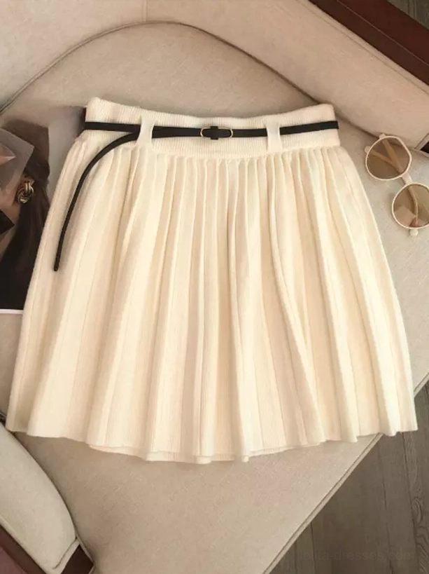 Off-white cream knitted pleated mini skirt with vertical pleats and black leather belt showing soft knit texture and A-line flare