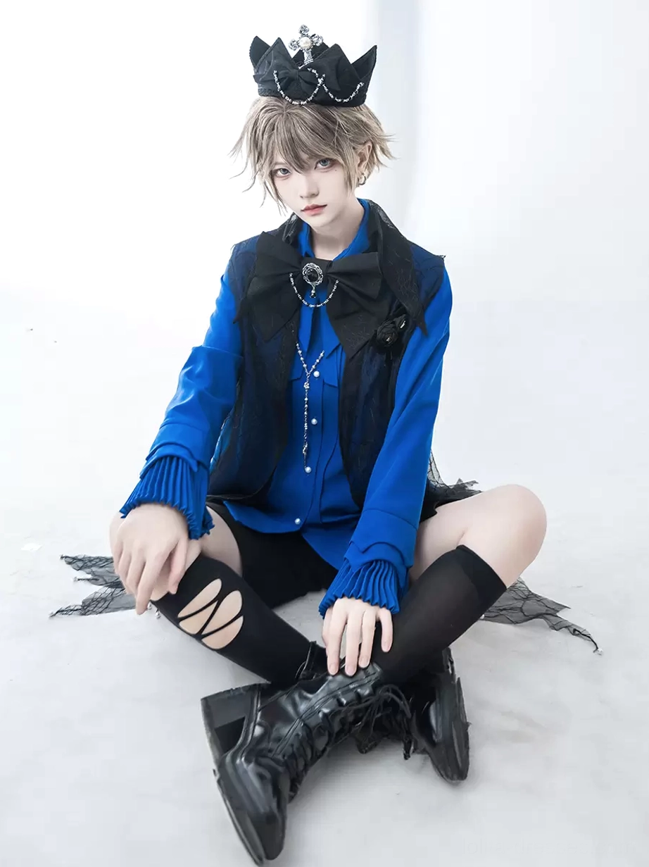 Ouji Lolita blouse with ruffled cuffs worn by model with crown headpiece ripped black stockings layered cross chain accessories sitting front view