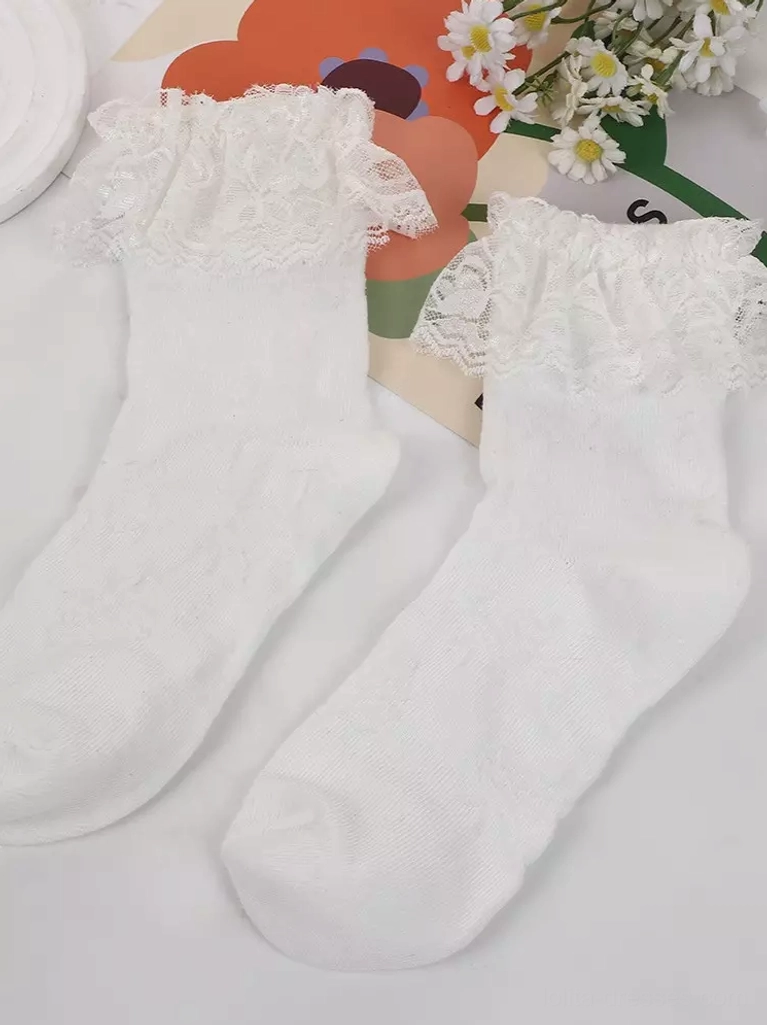 Pair of white cotton ankle socks with matching delicate lace ruffle cuffs, displayed on floral pattern background with decorative flowers