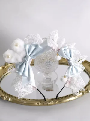 Pastel blue sweet lolita bunny ear headband with white lace trim and pom-pom charms, displayed on elegant gold mirror tray with ornate lace glass cup, featuring fluffy ears and satin bows with pearl decorations