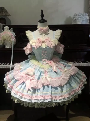 Pastel blue sweet lolita JSK dress front oblique view with cat paw bows tiered ruffle skirt pink satin bow trim displayed on dress form with piano backdrop