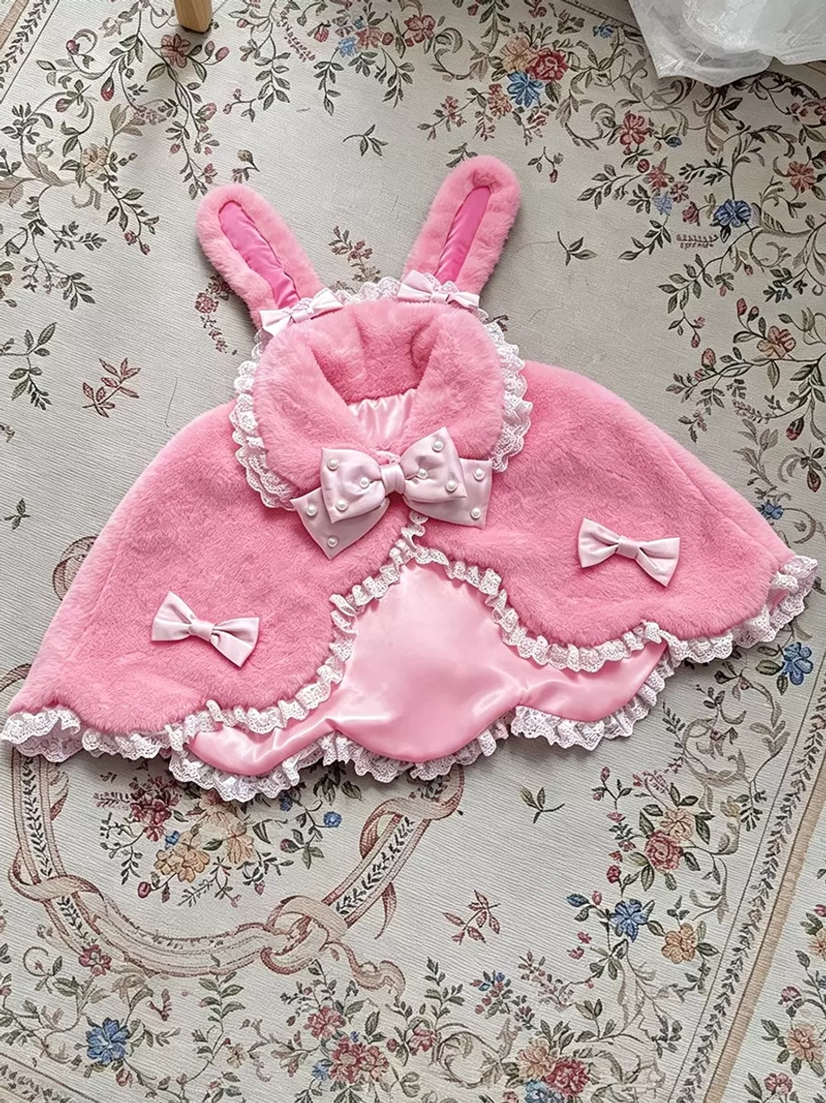 Pink fuzzy bunny ear plush lolita shawl with pink bows and delicate lace trim, top-down flat lay on vintage floral fabric