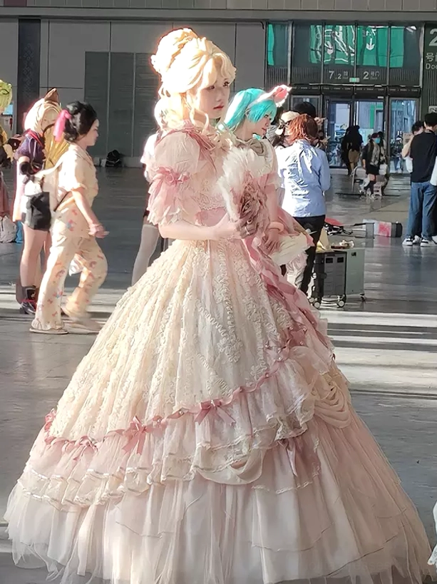 Pink cream lolita wedding dress worn by cosplayer updo hairstyle tiered ruffled skirt three quarter side view