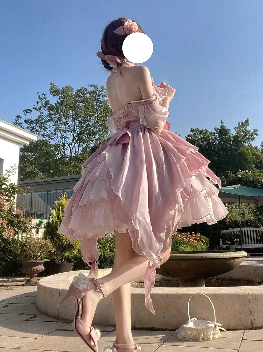 Pink fairy lolita gown rear side view with leg raised showing backless bare back design and irregular trailing hem with pink high heel sandals