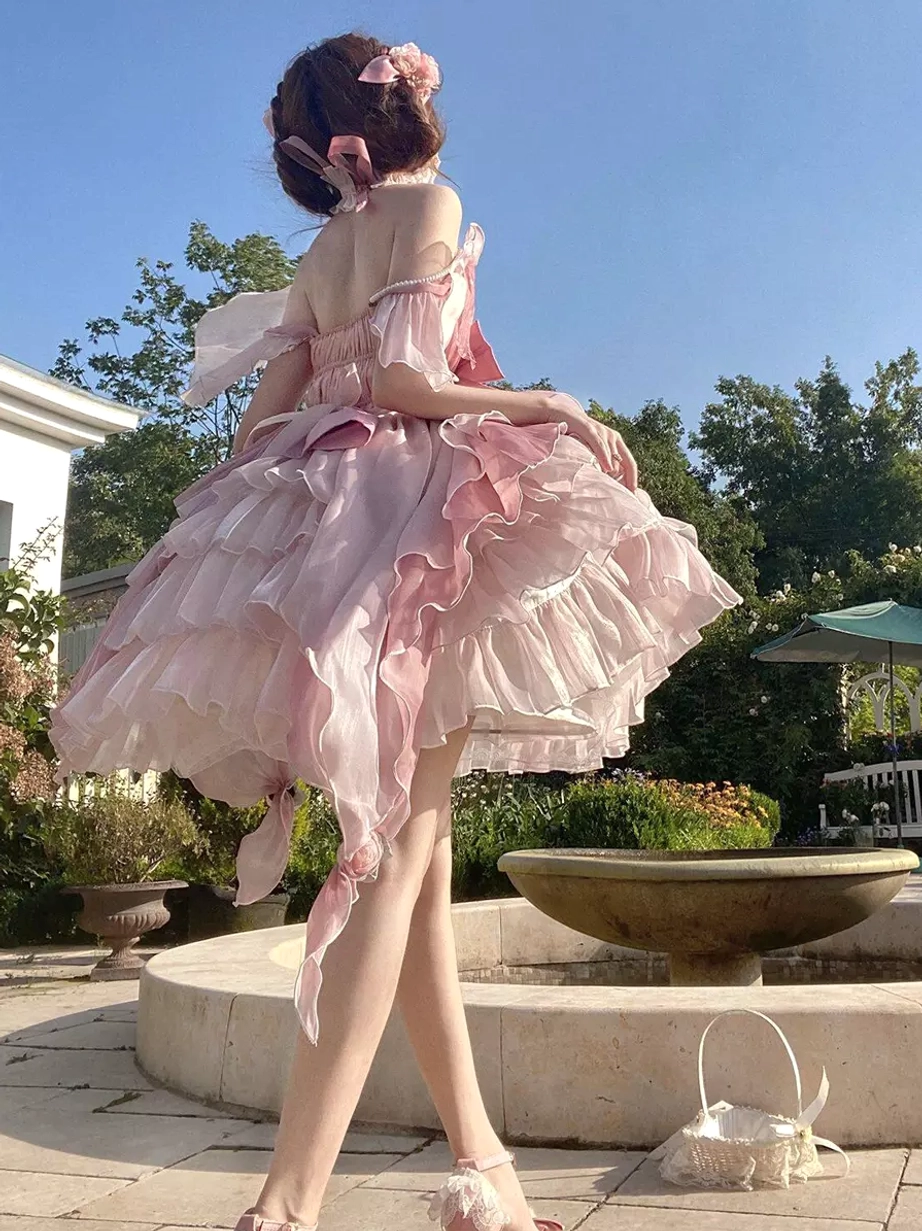 Pink fairy lolita princess gown rear side full view featuring backless off-shoulder style with ruffled layered skirt and side hair bow accessory