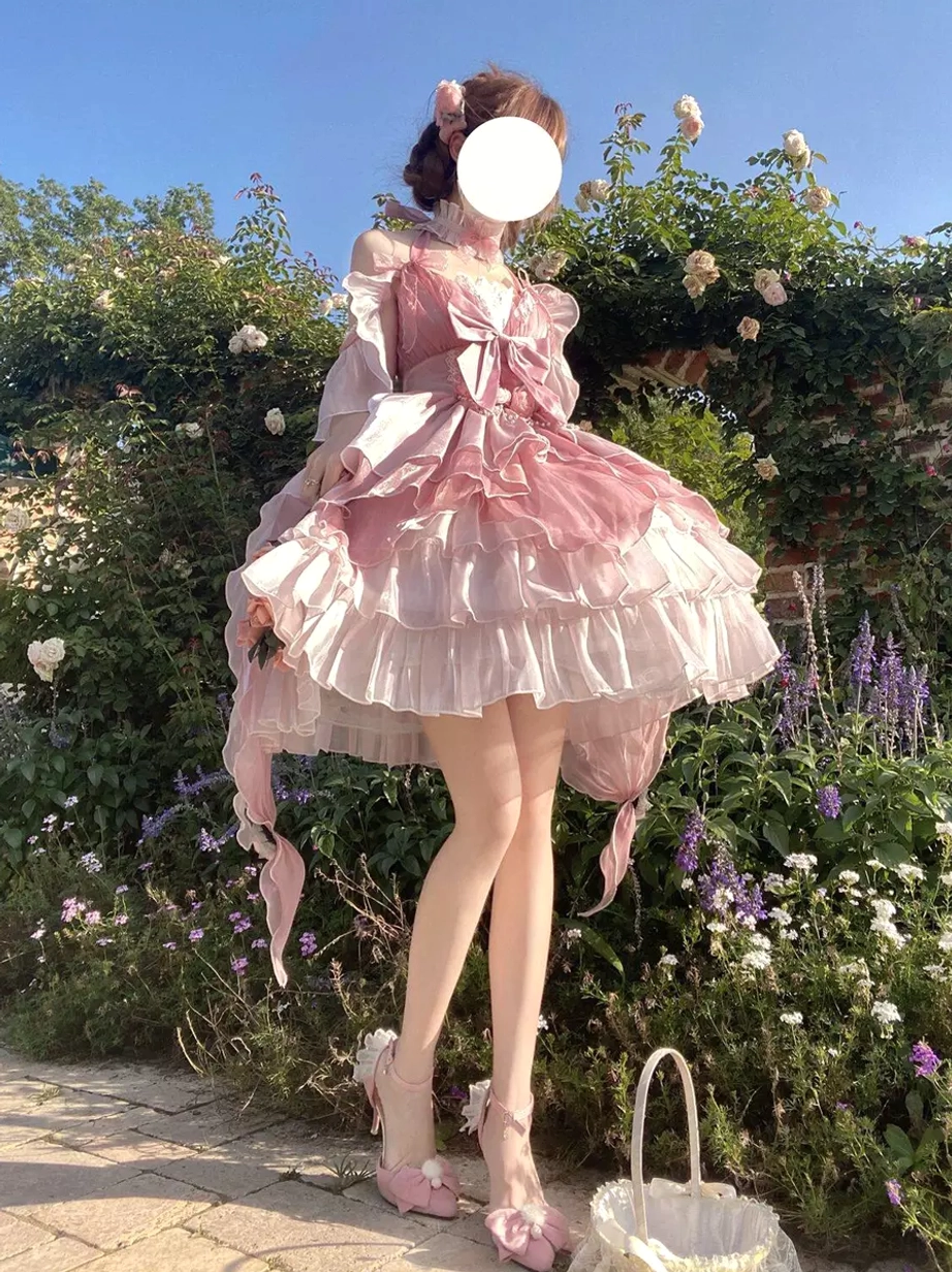 Pink fairy lolita princess gown side front view with off-shoulder halter neck design and chest bow embellishment in flower garden outdoor setting