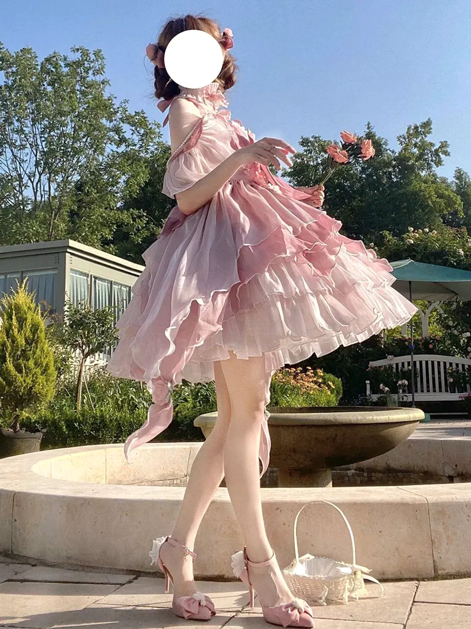 Pink fairy lolita princess gown side profile showing layered ruffled tulle skirt and off-shoulder sleeve details with pink flowers and hair bow accessory