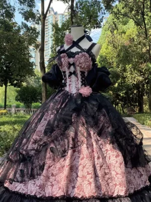 Pink gothic Lolita jumper skirt dress with black corset bodice and floral decorations shown on mannequin at eye level with park lawn background