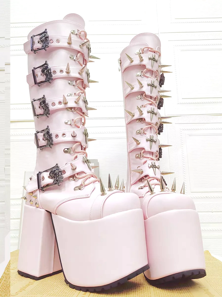 Pair of pink gothic punk platform boots side oblique view wall background oversized chunky heel skull buckles spike ornaments