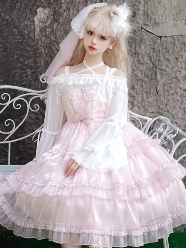 Pink sweet Hime Lolita dress front full view with cross halter neckline detail, veil hair accessory, and tiered tulle ruffled skirt against stone wall background