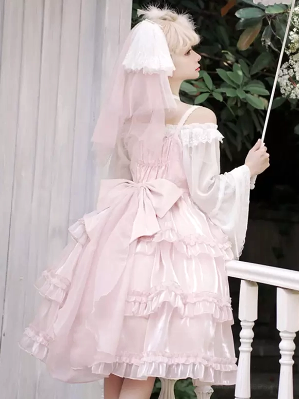 Pink sweet Hime Lolita dress side three-quarter view showcasing large back bow, off-shoulder silhouette, and volumetric layered skirt, styled with parasol on white railing balcony