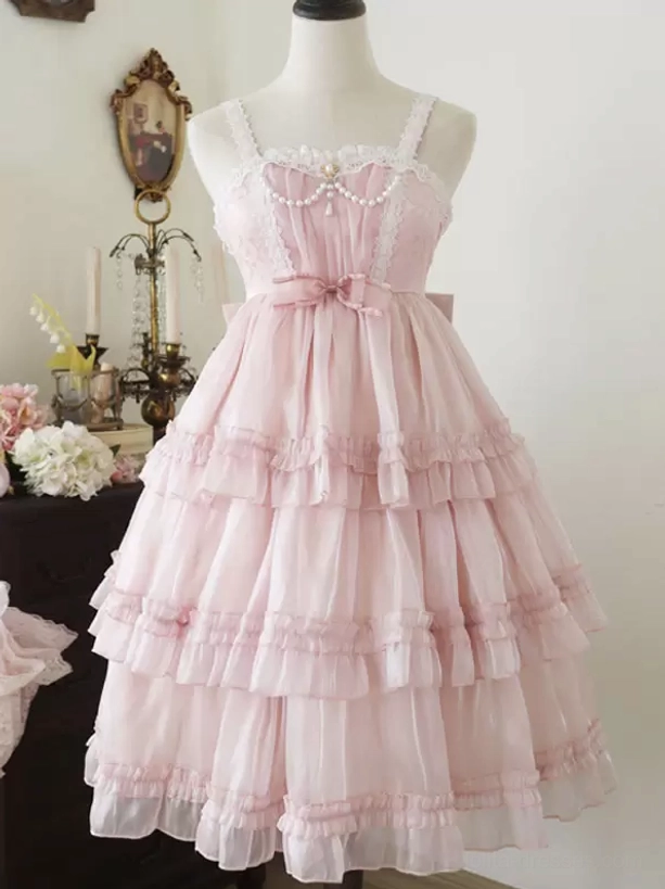 Pink sweet Hime Lolita dress front view with spaghetti straps, pearl neckline decoration, and tiered ruffled tulle skirt in vintage indoor room setting