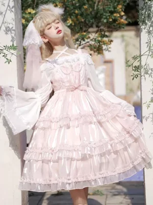 Pink sweet Hime Lolita jumper dress with pearl lace embellishments, off-shoulder white sleeves, and voluminous layered ruffled tulle skirt in front three-quarter outdoor garden view