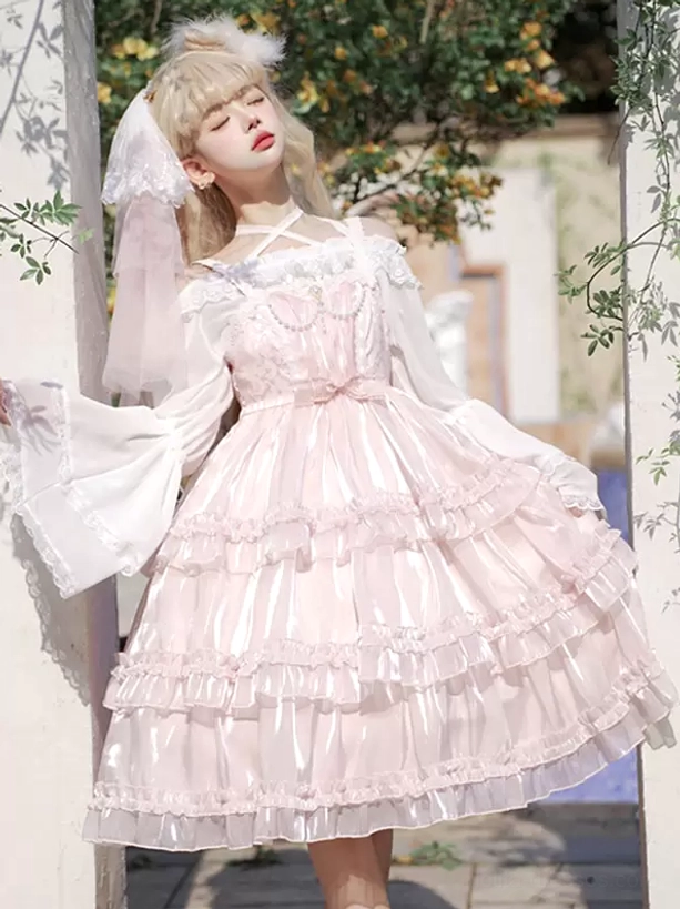 Pink sweet Hime Lolita jumper dress with pearl lace embellishments, off-shoulder white sleeves, and voluminous layered ruffled tulle skirt in front three-quarter outdoor garden view