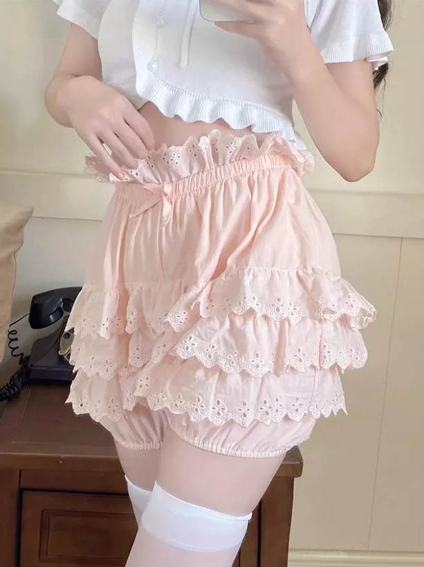 Front partial view of pink lolita bloomers with ruffled elastic waist, front bow accent, and layered lace ruffles indoors