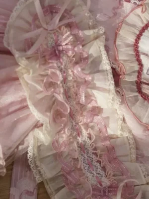 Close-up detail of pink Lolita headdress lace-up bonnet featuring ivory ruffled lace trim, layered frills, and delicate pink satin ribbons showcasing textile craftsmanship