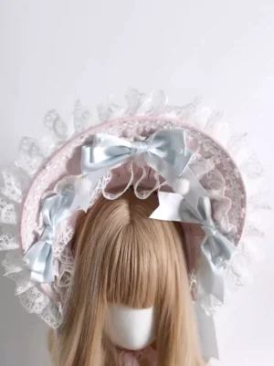 Pink sweet lolita bonnet with white lace trim and light blue satin bows close-up front view detailed embellishments