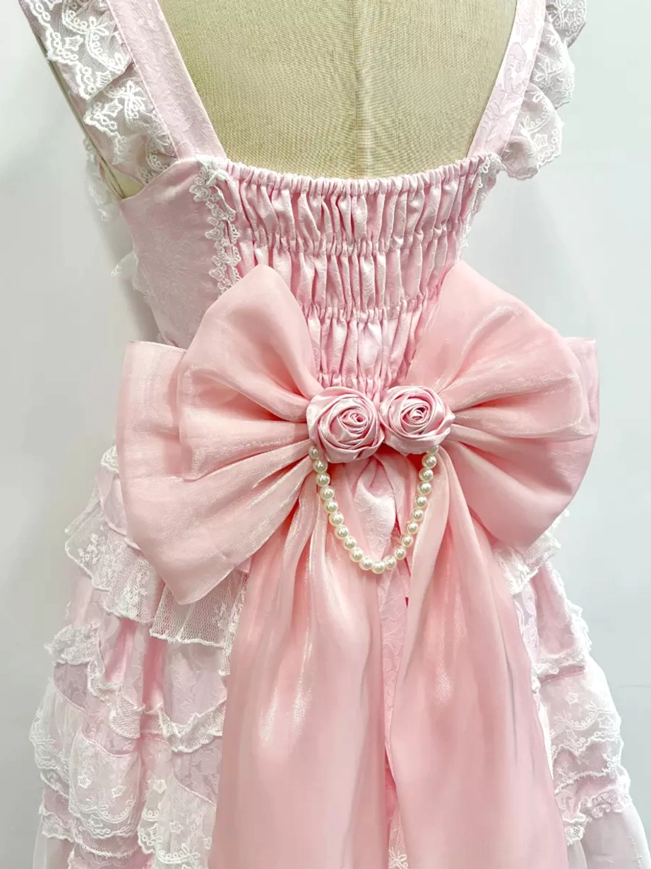 Close-up detail of pink Lolita bow tail accessory showing satin material roses pearl chain and shirred back construction