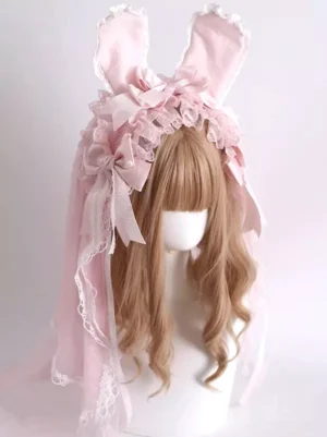 Pink lolita bunny ear headwear three-quarter front angle showing layered white lace accents, satin ribbon bows, draped tulle veil on mannequin with wavy wig