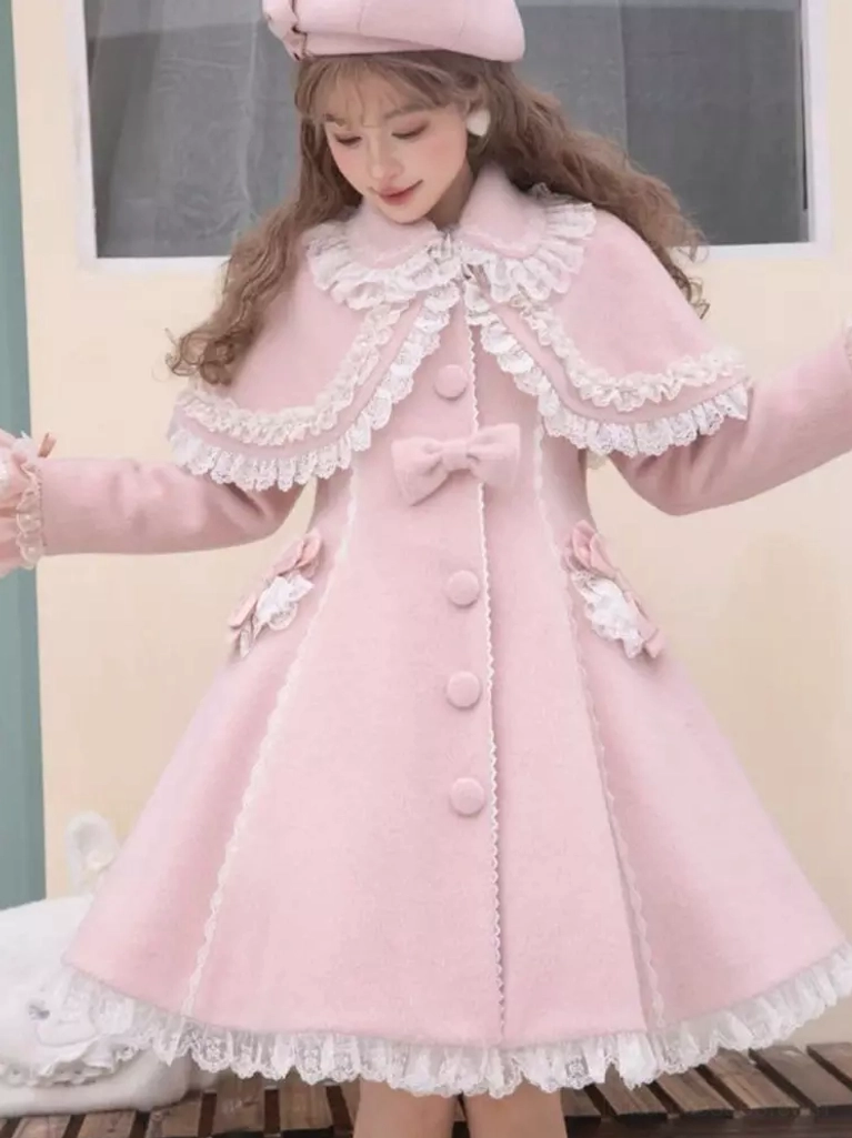 Pink lolita coat low front side angle by window showing intricate lace cape collar, side bow decorations, and lace hem trim details on sweet lolita ensemble