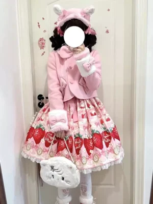 Cropped pink lolita coat with white fur cuffs, bow details, and strawberry print skirt pairing, styled with cat ear fuzzy headpiece for sweet aesthetic