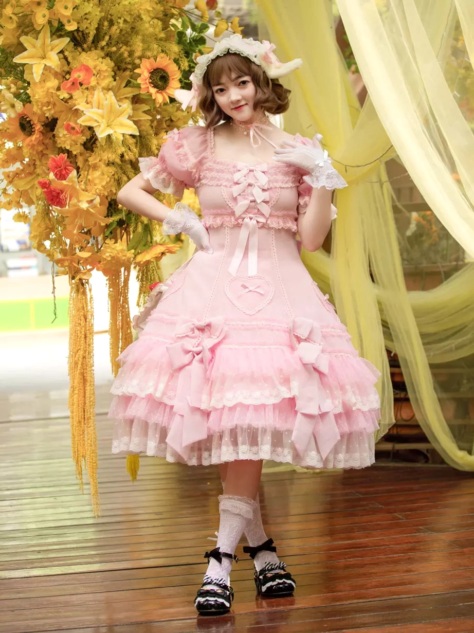 Pink Lolita dress front three-quarter pose displaying puffed sleeves lace gloves and decorative hair accessory