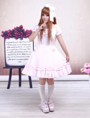 Pink lolita dress full front view on model wearing white knee socks and pink platform shoes, showcasing square neckline, puff sleeves, and side skirt bows