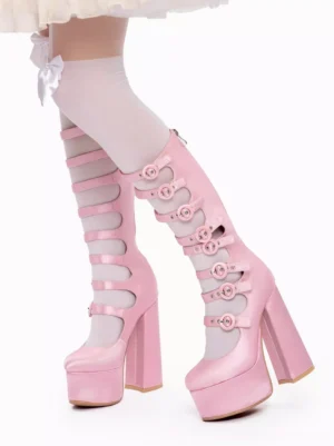 Close-up front-side view of pink lolita platform boots with cut-out strap design worn with white bow-decorated thigh-high socks and ruffled skirt hem