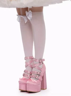 Front view of pink satin lolita shoes with dual criss-cross riveted straps, metal buckle closures, thick platform heel, white thigh-high stockings with bow details on white skirt